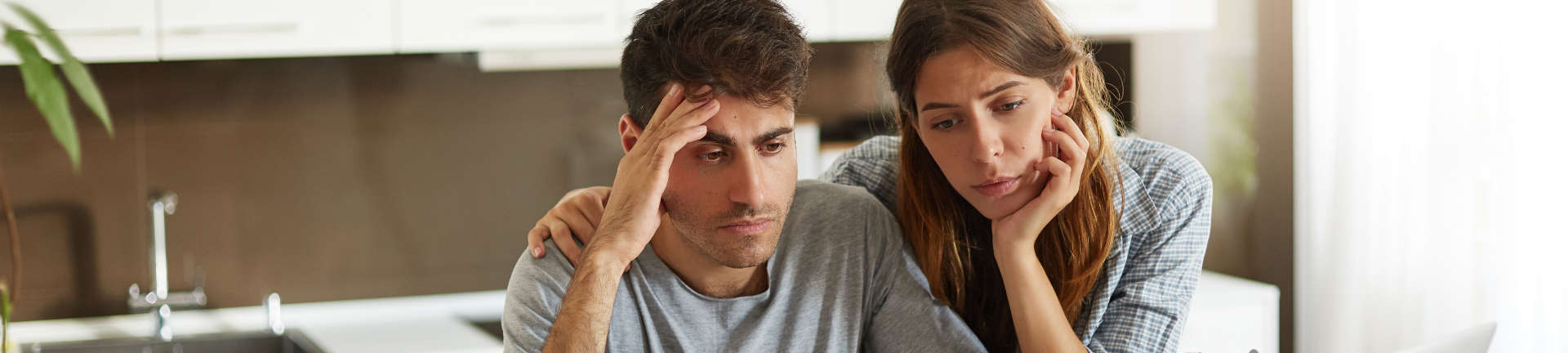 Depressed young couple studying documents and looking for a Bankruptcy Lawyer on Internet