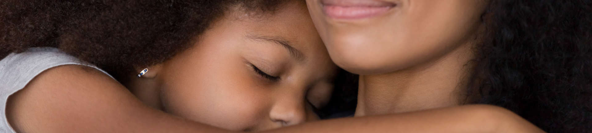 A little girl sleeping and cuddling the assisting woman