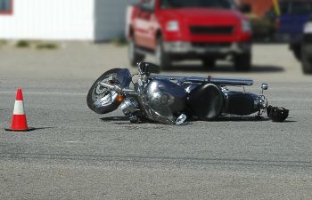 A motorcycle lying on the road after being hit by car.