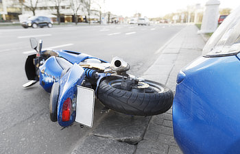 the road the motorcycle lies on the road near the car